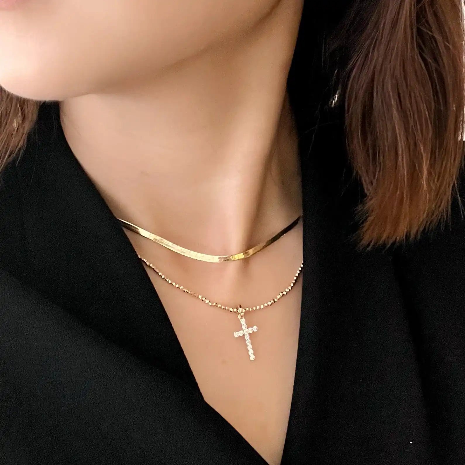 Two gold necklaces, one with a cross pendant.