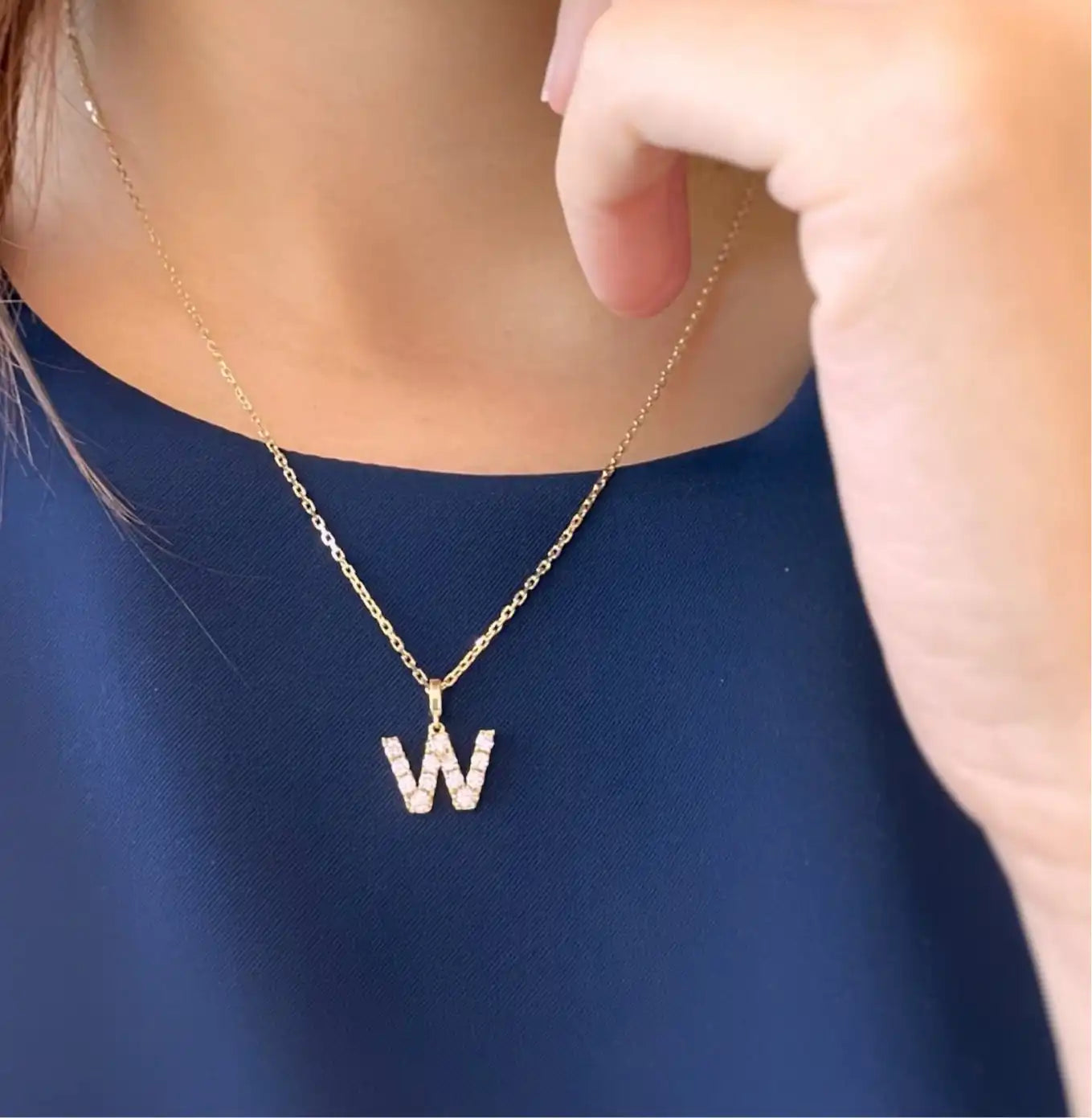 Gold necklace with diamond-studded ’W’ pendant.